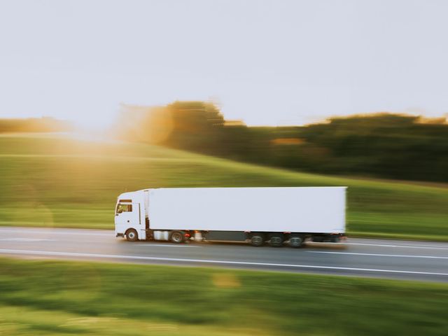 un semi-remorque blanc circulant sur une route de campagne